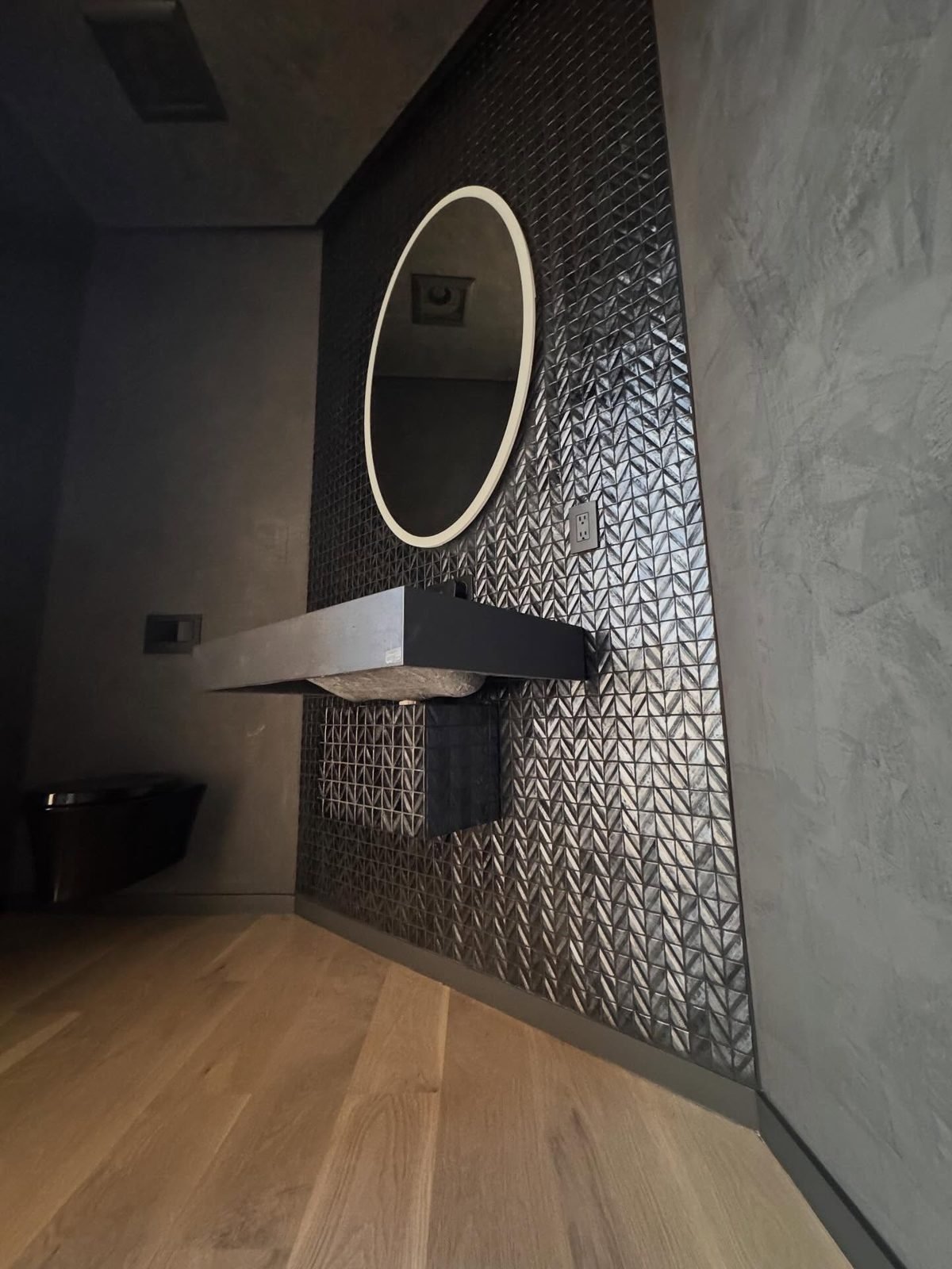 Powder room with herringbone feature wall and backlit mirror